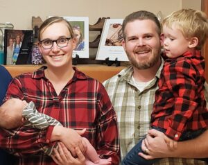 Picture of Rachel cradling their baby Joseph and Mark holding his three-year-old son Daniel.